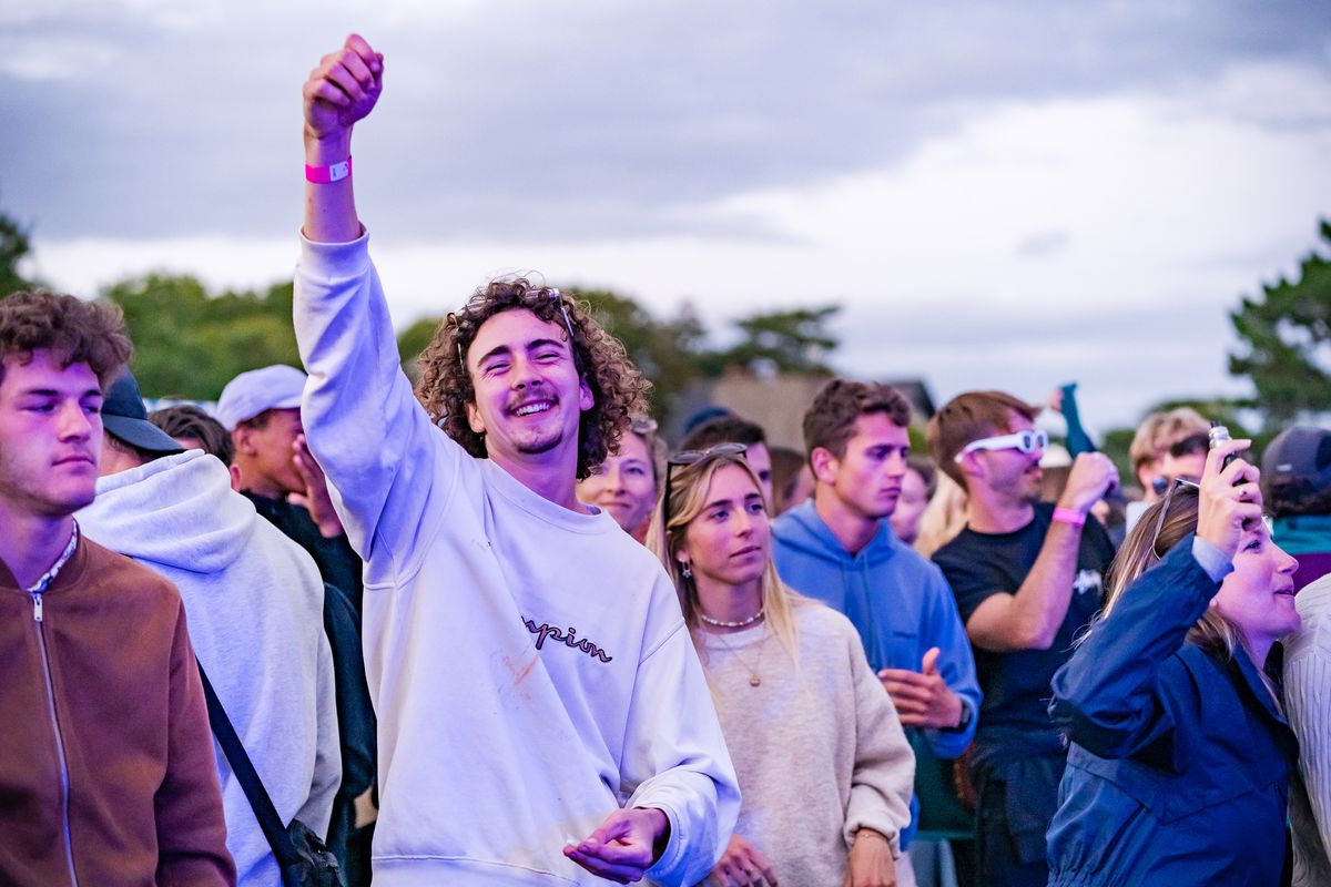 Festivalier bras levé dans la foule en soirée